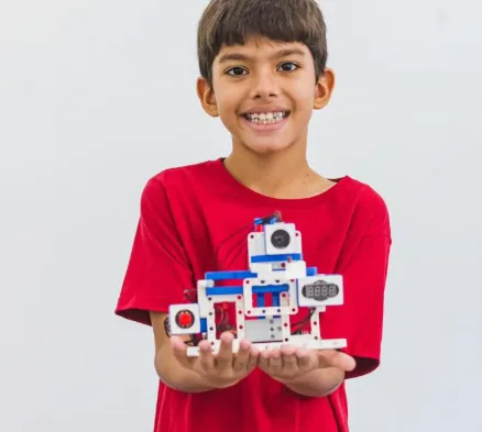 Aluno com o robô que montou com o kit da Student Maker