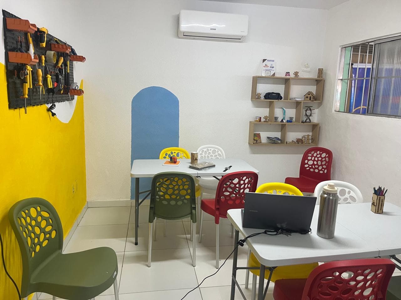 Sala de oficina do Clube de Robótica, com bancada de ferramentas e mesas de trabalho