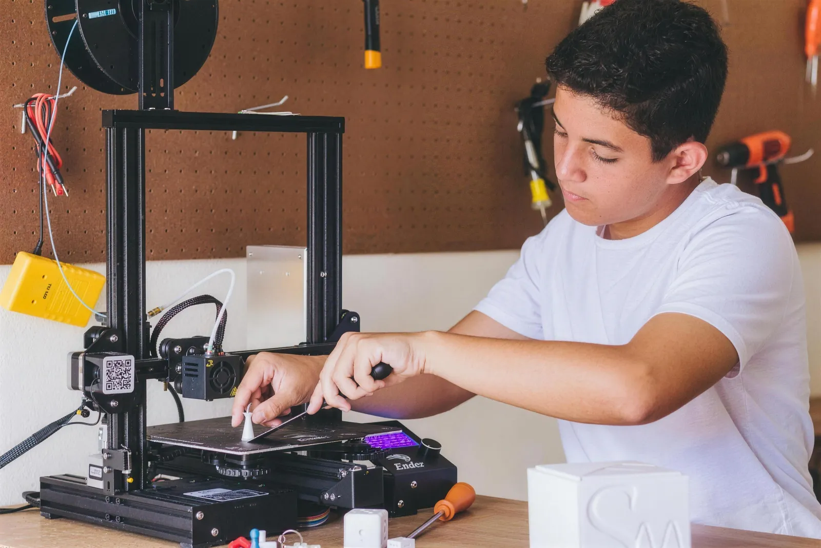 Aluno operando a impressora 3D no espaço maker